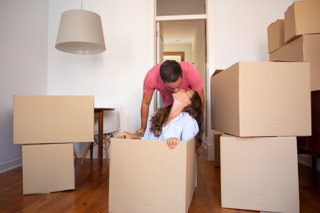 happy-young-man-dragging-box-with-his-girlfriend-inside-kissing-her_74855-10210